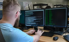 A programmer works on code across multiple computer monitors.