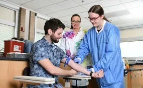 Student practicing on patient with teacher behind
